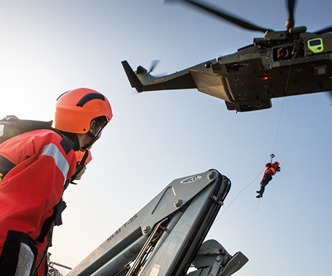 Hjemmeværnssoldater venter på Marinehjemmeværnsfartøj mens person fires ned fra helikopter